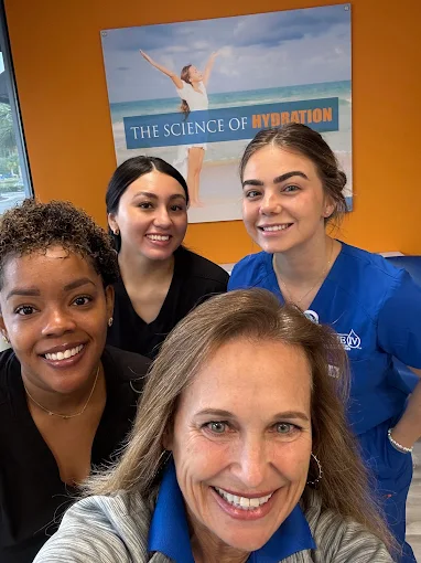 The Prime IV Hydration & Wellness Bluffton team smiling together beneath the Science of Hydration wall art